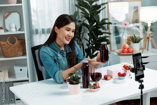 Cuadro en lienzo Smiling young beautiful Asian reviewing tasty mixed strawberry and cherry juice detox drinks, showing healthy product to promote for special promotion selling on social media online record
