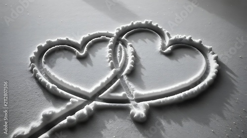 Two intertwined heart shapes drawn in snow symbolizing love, connection, and emotional warmth in winter