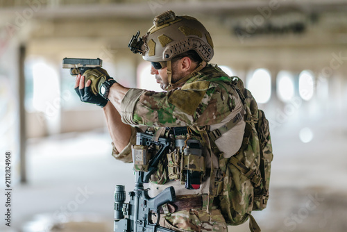 Bild auf Leinwand Military tactical operator aims pistol during sidearm drill in abandoned concret
