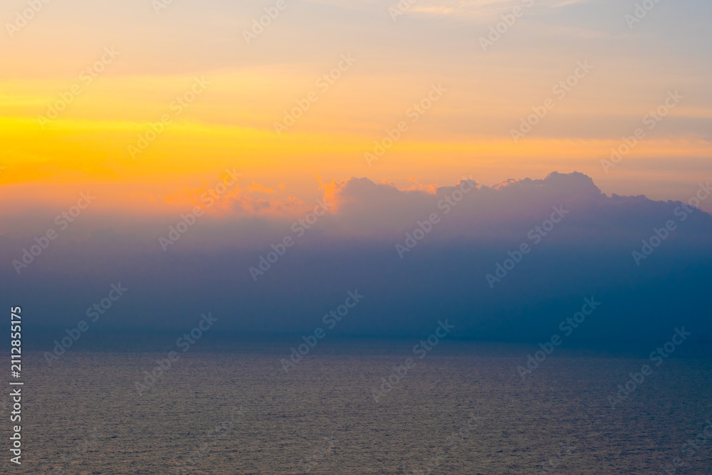 Fototapeta premium Enjoy the panoramic view of the horizon, the sunrise with colorful clouds and beautiful cloud patterns in the soft morning light, contrasting with the golden reflection of the sea.