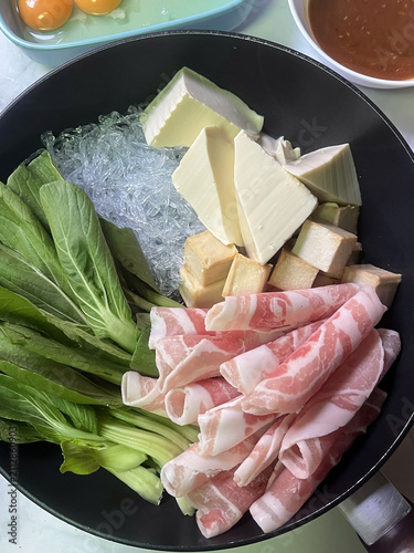 Konstfotografi Fresh pork slices bok choy tofu glass noodles and bamboo shoot in hot pot with d
