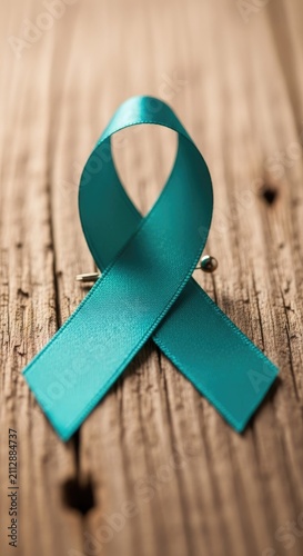 Close up of teal awareness ribbon on wood.