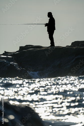 磯で釣りをする人物シルエット｜趣味や休日イメージに使える海景写真