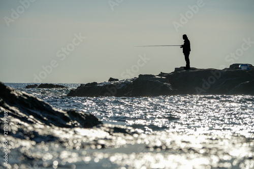 磯で釣りをする人物シルエット｜趣味や休日イメージに使える海景写真