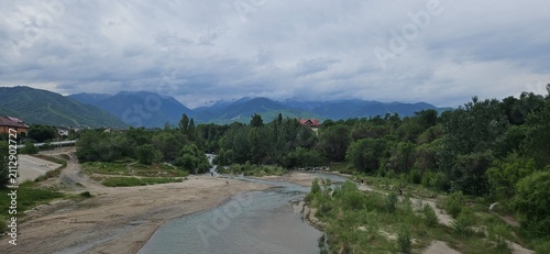 Scenic mountain river flowing through valley with snowcapped peaks under cloudy sky