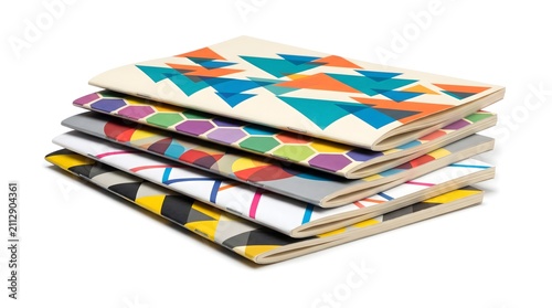 Colourful pile of zines with bold geometric cover art on a white surface