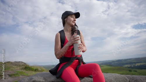 Enjoying a drink on a rocky hilltop with a view of the landscape under a cloudy sky