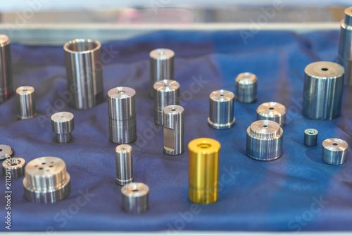 Precision machined metal cylinders and components on blue fabric