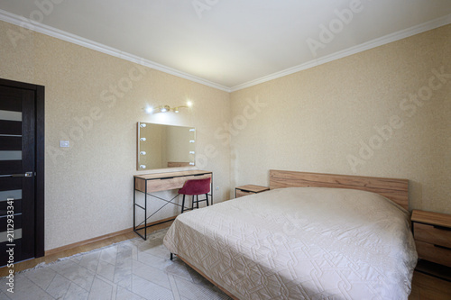Foto cozy bedroom features a bed with a wooden headboard, a vanity with a lighted mir