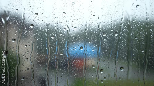Close up of raindrops on glass, raindrops sliding off the glass outside the window