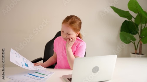 Child looks at papers and thinks at home office in morning