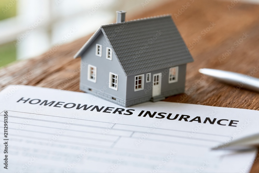 Fototapeta premium Model house on homeowners insurance document with pen, symbolizing property protection and financial security.