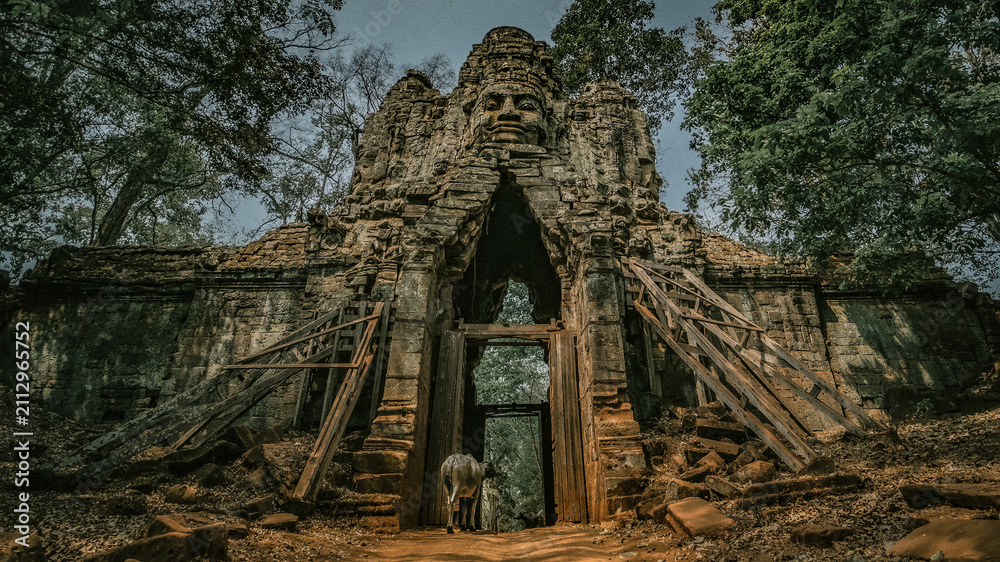 Fototapeta premium Ancient stone stone face entrance gate with scaffolding at Angkor Thom temple complex in Siem Reap, Cambodia