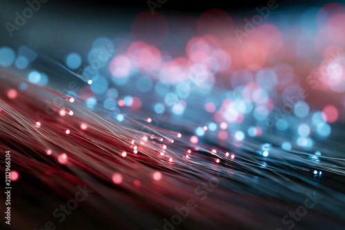 Fiber optics glow with red and blue light. Tiny luminous dots pulse softly along strands. Depth of field blurs background into dreamy bokeh. Technology feels alive and connected