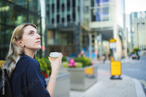 Foto Young woman contemplating the city skyline while holding a disposable coffee cup
