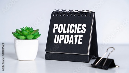Professional policies update announcement with clipboard and green plant on white desk