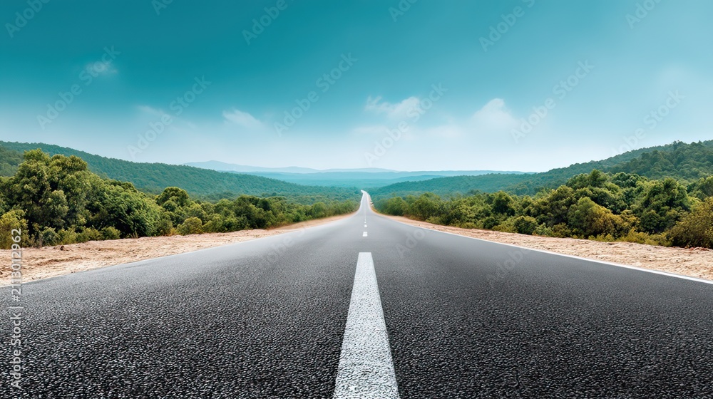 Fototapeta premium Scenic winding road through serene green landscape with vibrant trees under a clear blue sky on a sunny day