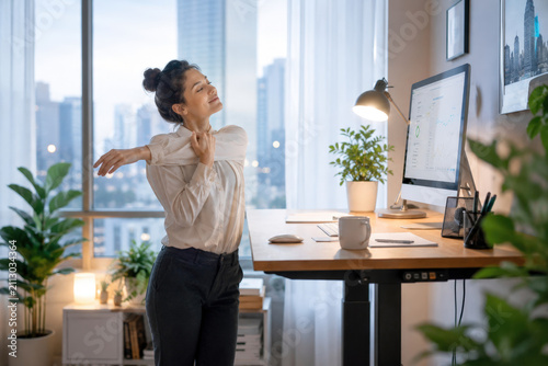 Woman Stretching Arms Standing At Adjustable Height Desk In Office