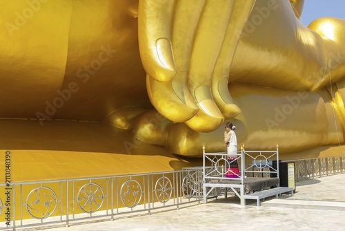 Thailand's largest Buddha statue (Luang Pho Yai), Thai woman, Wai gesture (traditional gesture of respect, greeting or thanks), Wat Muang, Ang Thong, Amphoe Wiset Chai Chan province, Thailand