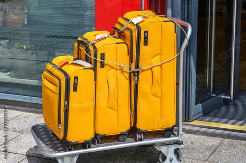 Three bright yellow suitcases secured with a cable lock on a luggage trolley