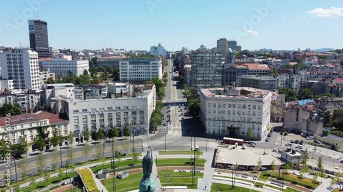 Aerial view pulling back over a busy city avenue and buildings in downtown Belgrade on a sunny day.
