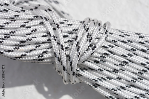 Close up view of a coiled white synthetic rope with black tracer lines