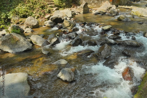 river, Clear mountain stream flowing over natural rocks in a tropical forest, creating a fresh and peaceful nature landscape under daylight.