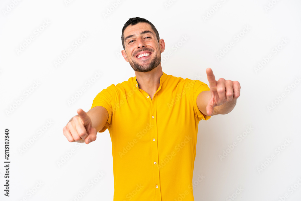 Fototapeta premium Young handsome caucasian man isolated on white background pointing front with happy expression
