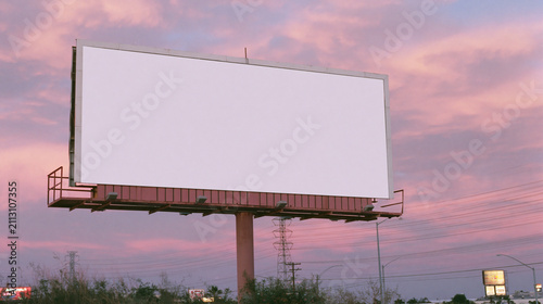Blank white billboard mockup at sunset along desert highway