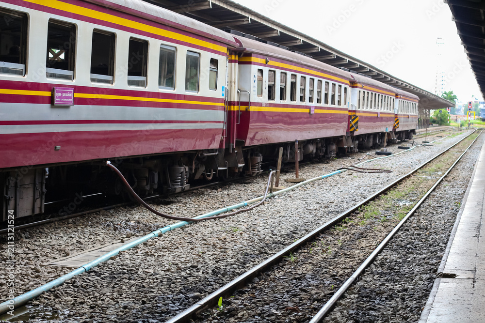 Fototapeta premium Maroon and yellow train cars parked at a station with multiple tracks