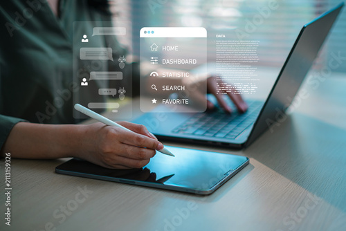 Business person using stylus pen on digital tablet with laptop and virtual AI chat assistant interface, concept of remote work and digital workflow