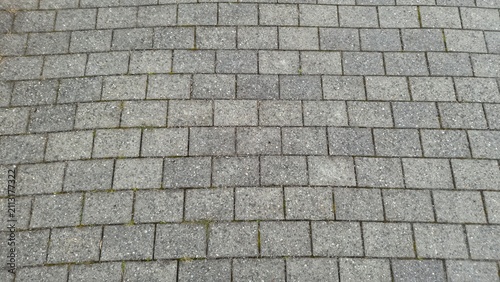 Paved walkway with gray stones and some green grass