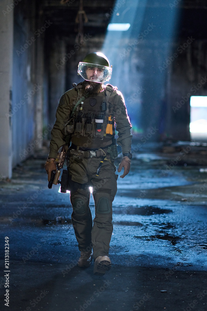 Fototapeta premium Armed Tactical Soldier in Military Gear Walking Through Abandoned Urban Building With Helmet Visor