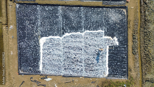 Aerial View of Traditional Salt Production Workers, Salt Farmers Raking Sea Salt in Evaporation Ponds, on pati, indonesia