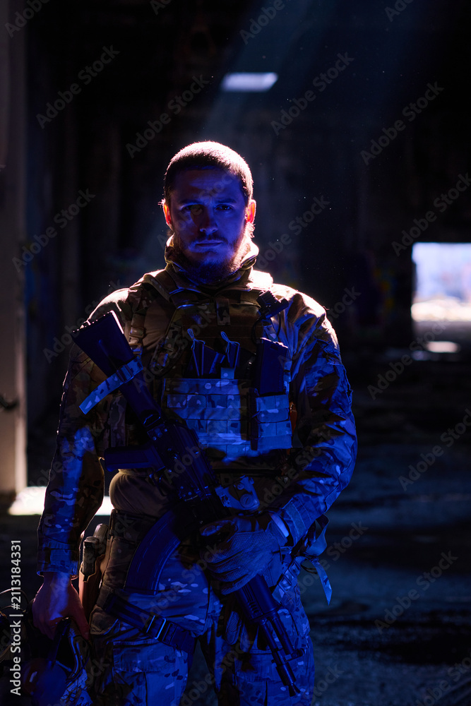 Obraz premium Tactical Soldier In Camouflage Gear Holding Rifle Under Dramatic Night Light In Urban Ruins