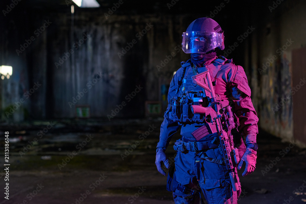 Obraz premium Armed Tactical Soldier In Riot Helmet And Plate Carrier Holding Assault Rifle In Abandoned Warehouse