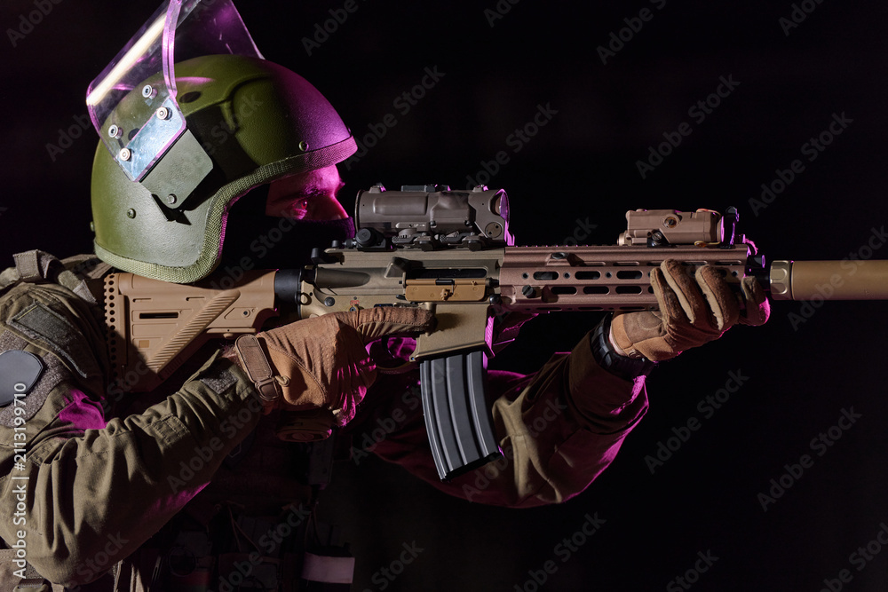 Obraz premium Soldier Aiming Tactical Rifle With Helmet, Night Optics And Suppressor In Low Light