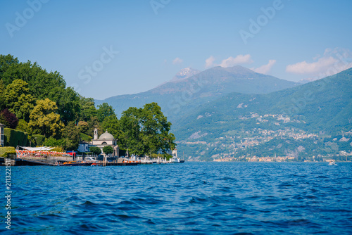 Photography Scenic view of Lake Como with lush greenery, mountains in the background, and a