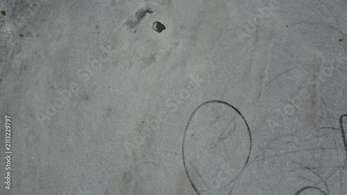 Tire marks and a circular patch on a gravel surface in the afternoon light