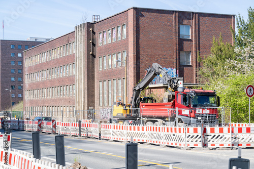 Bagger belädt Kipplaster auf einer abgesperrten Straßenbaustelle