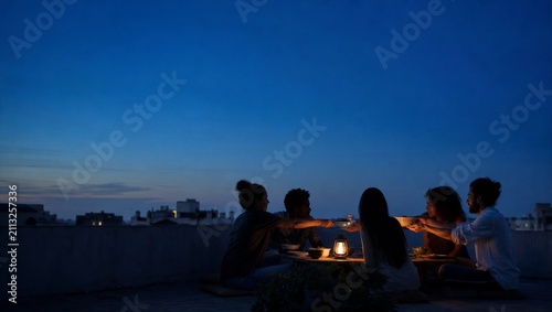 Woman and man sharing dinner on rooftop terrace at twilight. Group of friends passing bowls around a solar lantern table. Urban community dining concept