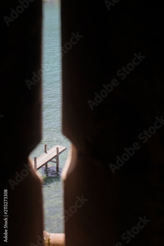 Foto Scenic view of a wooden pier on Lake Geneva through a historic stone arrow slit inside Chillon Castle, Switzerland