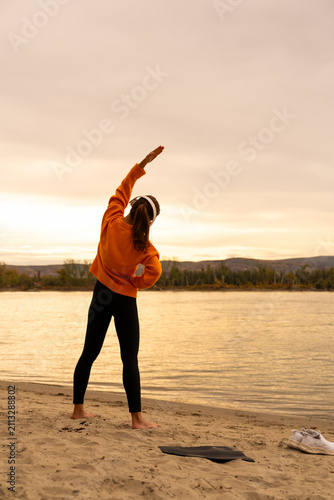 Active woman exercising outdoors by the river during golden hour