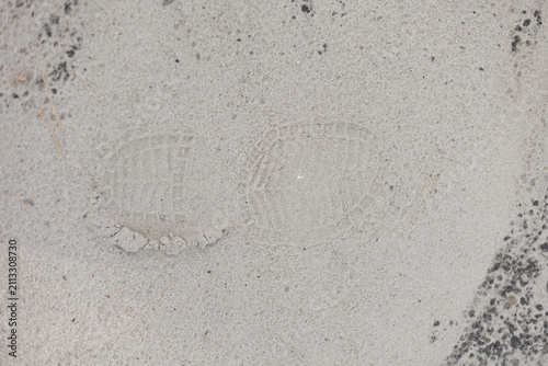 Single boot footprint imprint in grey sand texture close up