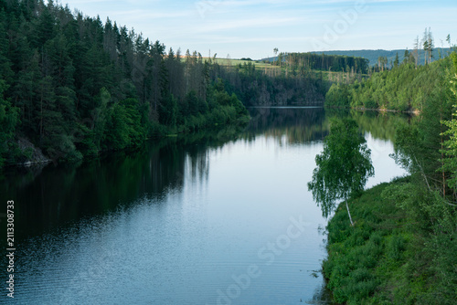 Scenic Summer View of a Lake Reservoir Surrounded by Lush Green Pine Forests in the Czech Republic