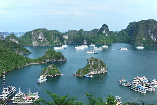 Konstfotografi A panoramic view showcases several cruise boats sailing gracefully around the towering limestone karsts of Ha Long Bay, Vietnam, highlighting its natural grandeur and iconic seascape