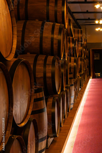 Bild auf Leinwand Stack of Oak Wine Barrels in a Traditional Winery with Red Carpet