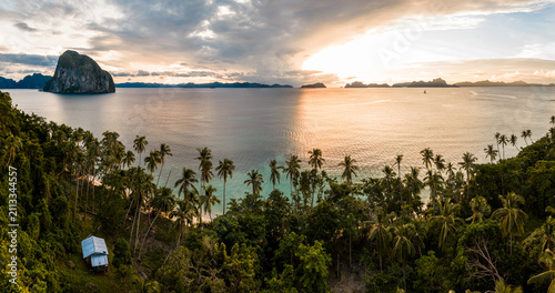 Tropical beach with palm trees on Palawan, the Philippines at sunset
