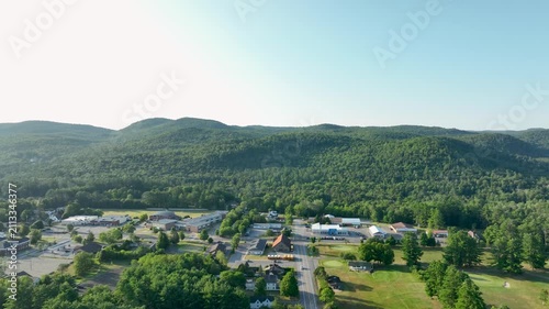 Aerial view of Court Street in Elizabethtown, New York, surrounded by forested Adirondack mountains under clear summer skies.