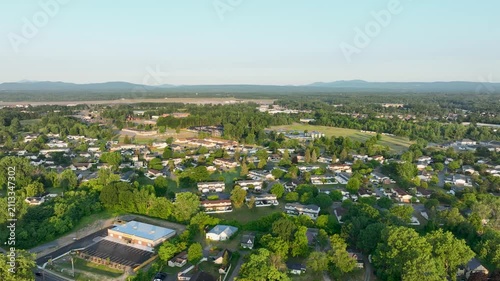 Aerial view of residential neighborhoods in Plattsburgh, New York, with Adirondack Mountains, green landscapes, and golden evening summer light.